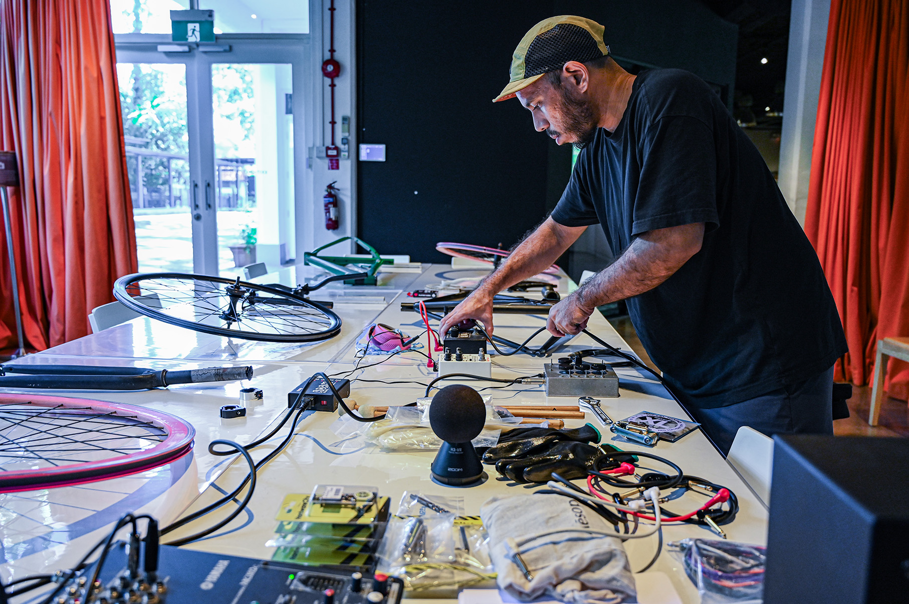 an artist preparing a table of bicycle parts and music equipment