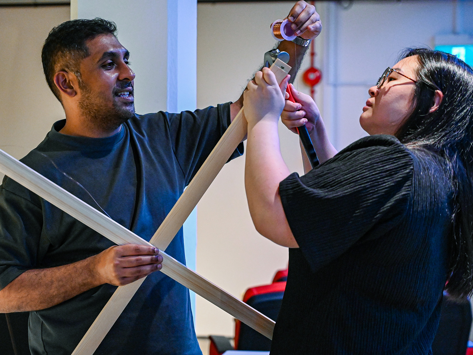 Two people making an antenna out of wooden sticks