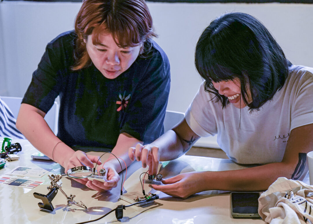 Two woman tinkering with electronics