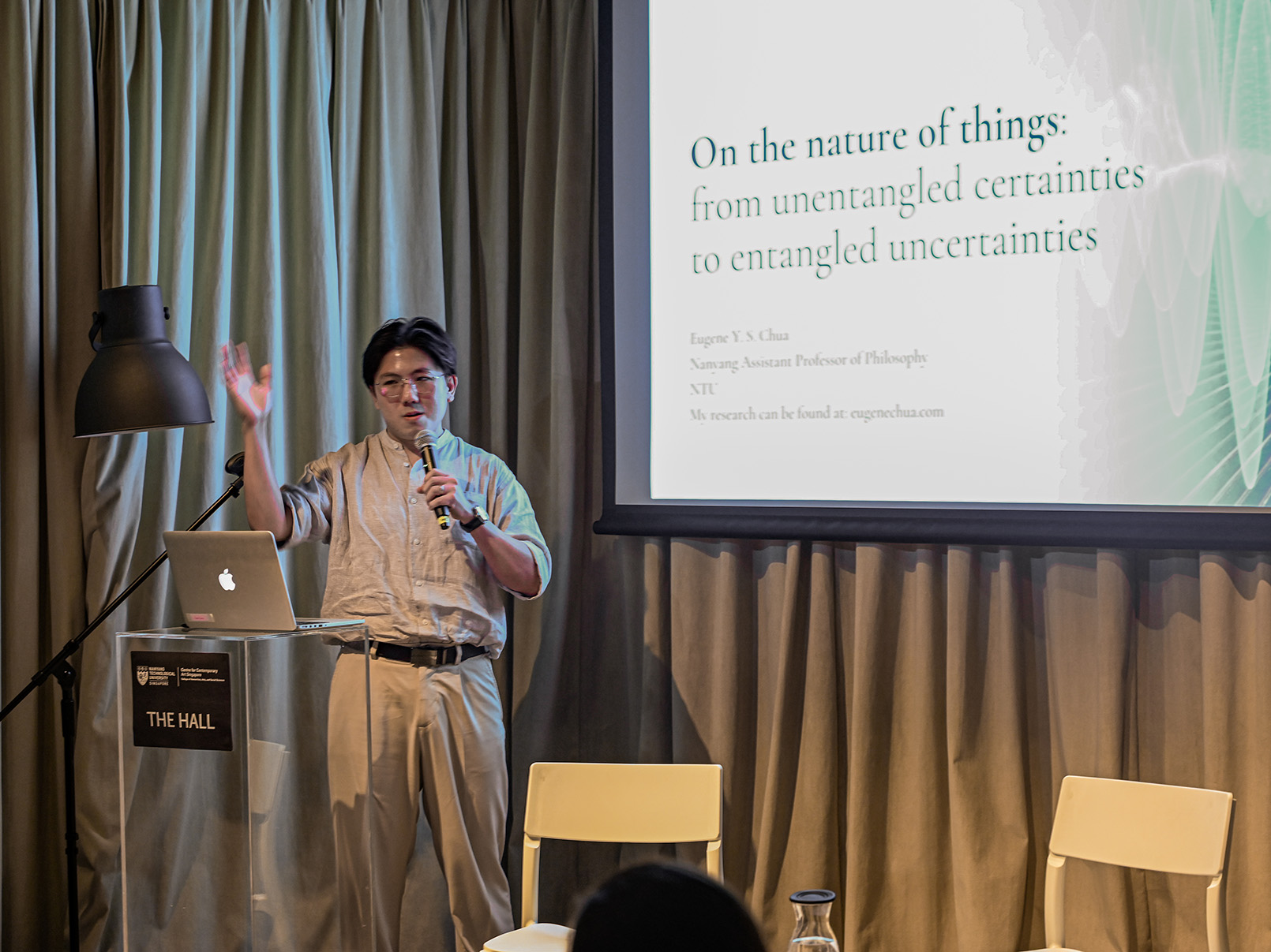 a man giving a lecture in front of a projected screen