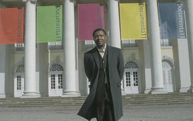 Image: Okwui Enwezor in front of the Museum Fridericianum during Documenta11, 2002. Photo: Ryzard Kasiewic. Courtesy Documenta Archive.